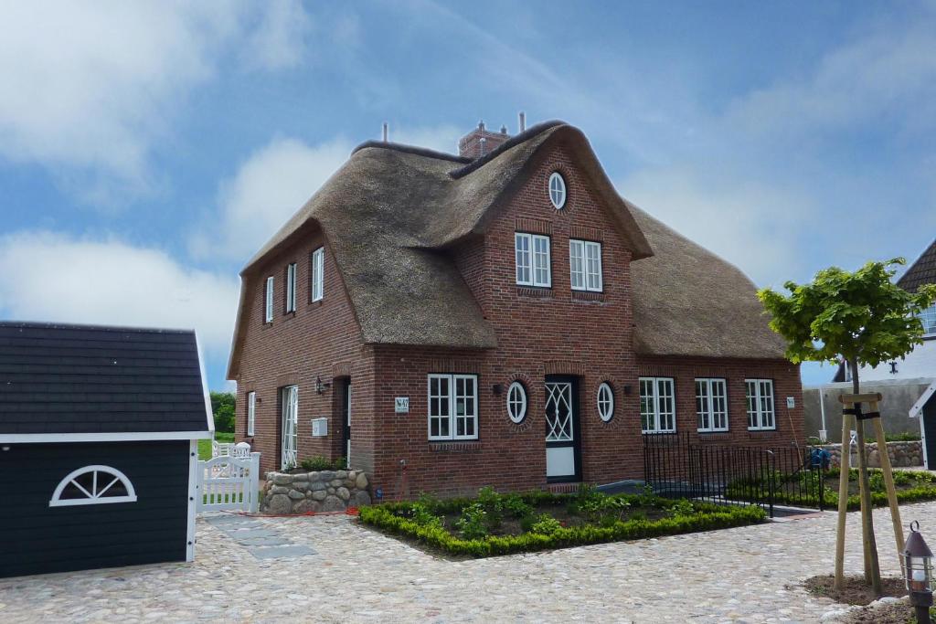 a large red brick house with a thatched roof at Hüs Lillebo in Hedehusum