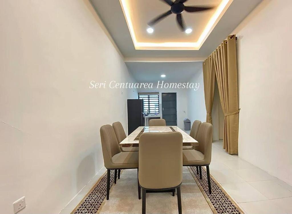 a dining room with a table and chairs and a ceiling fan at Seri Centuarea Homestay, Seri Iskandar in Seri Iskandar
