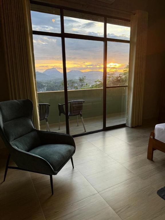 a living room with a chair and a large window at Mystay in Kandy
