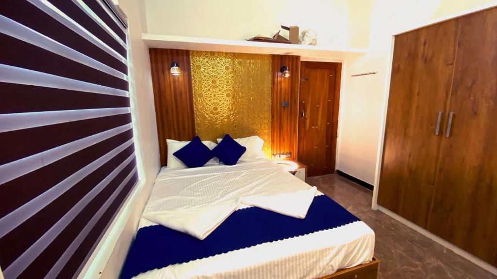a bedroom with a bed with blue and white pillows at Karmalhills Homestay in Tindummal