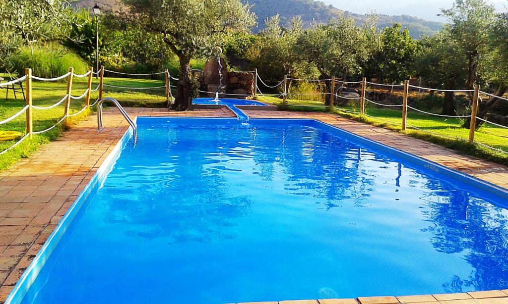 a swimming pool with blue water in a yard at Hotel Rural Hosteria Fontivieja in Losar de la Vera