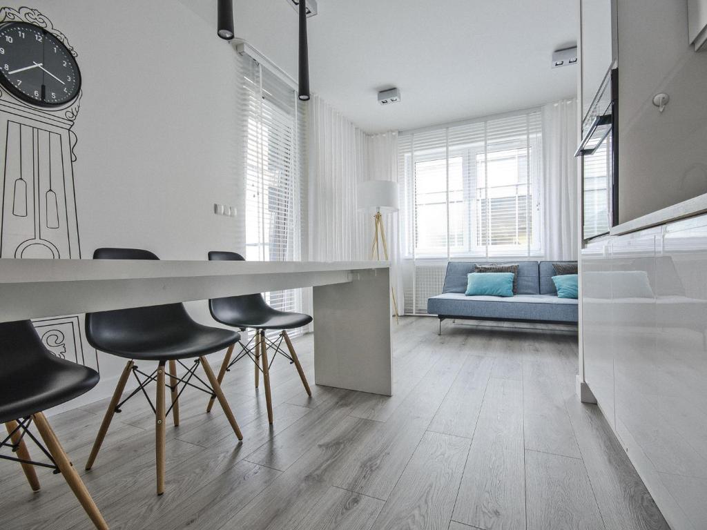 uma sala de estar com mesa e cadeiras e um relógio em Ataner Apartamenty em Koszalin