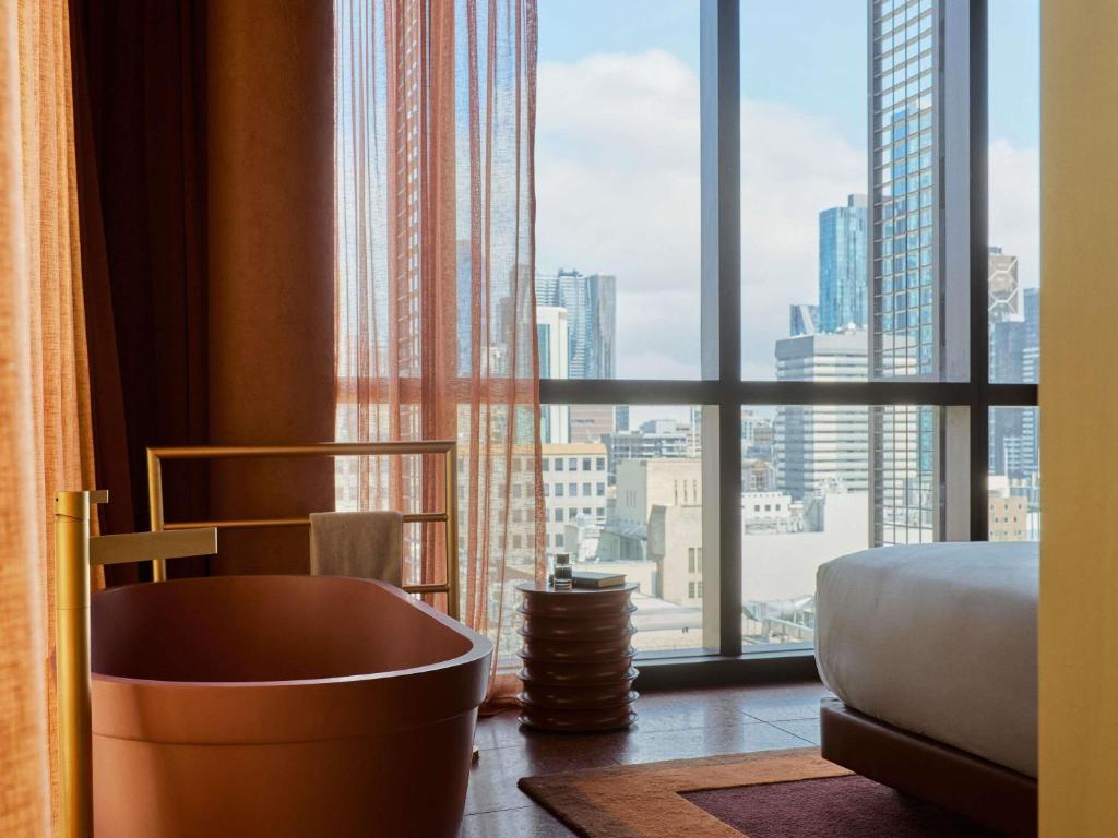 een badkamer met een bad voor een raam bij Hyde Melbourne Place in Melbourne