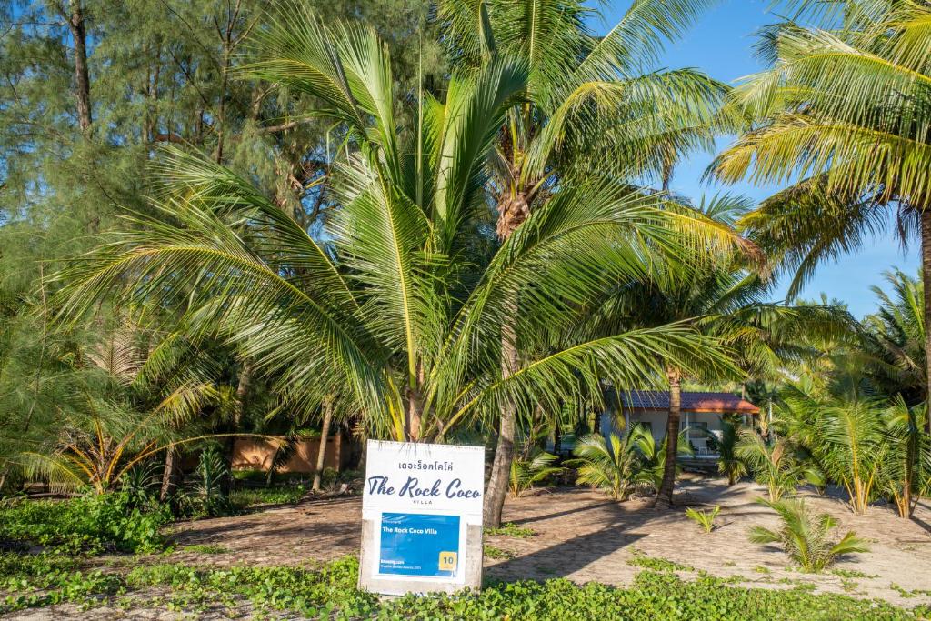 a palm tree with a sign in front of it at The Rock Coco Villa in Ban Laem Pom