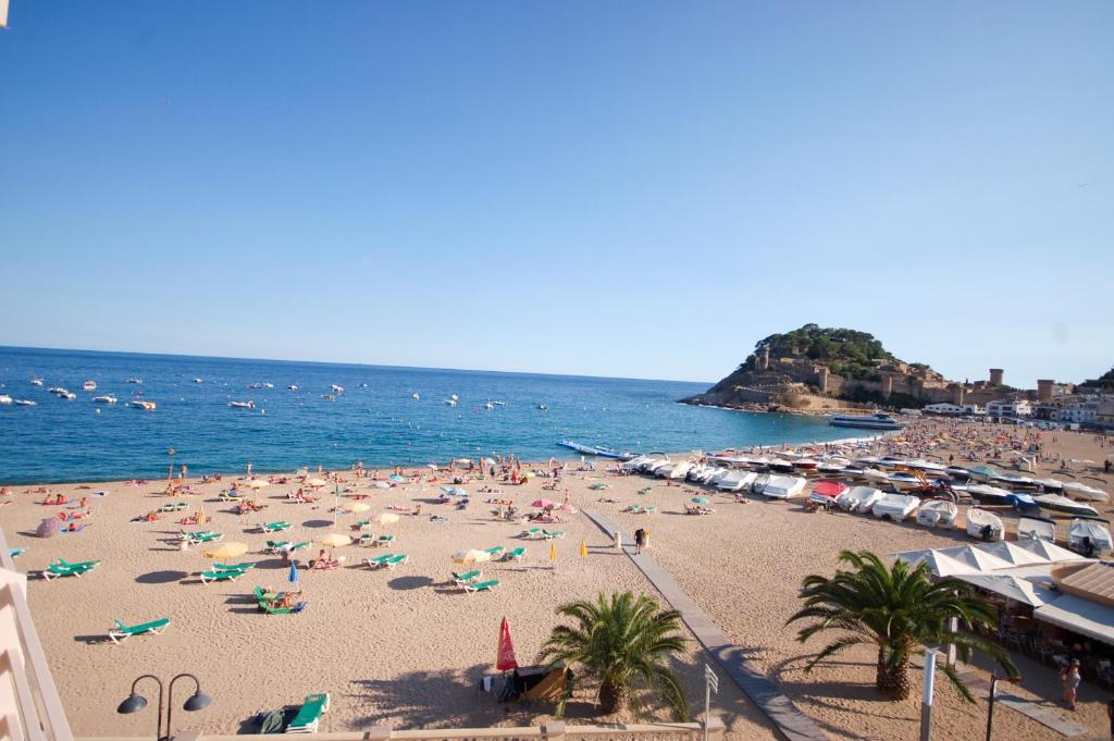 a beach with a lot of people and the ocean at Lets Holidays Tossa de Mar Beach Apartment in Tossa de Mar