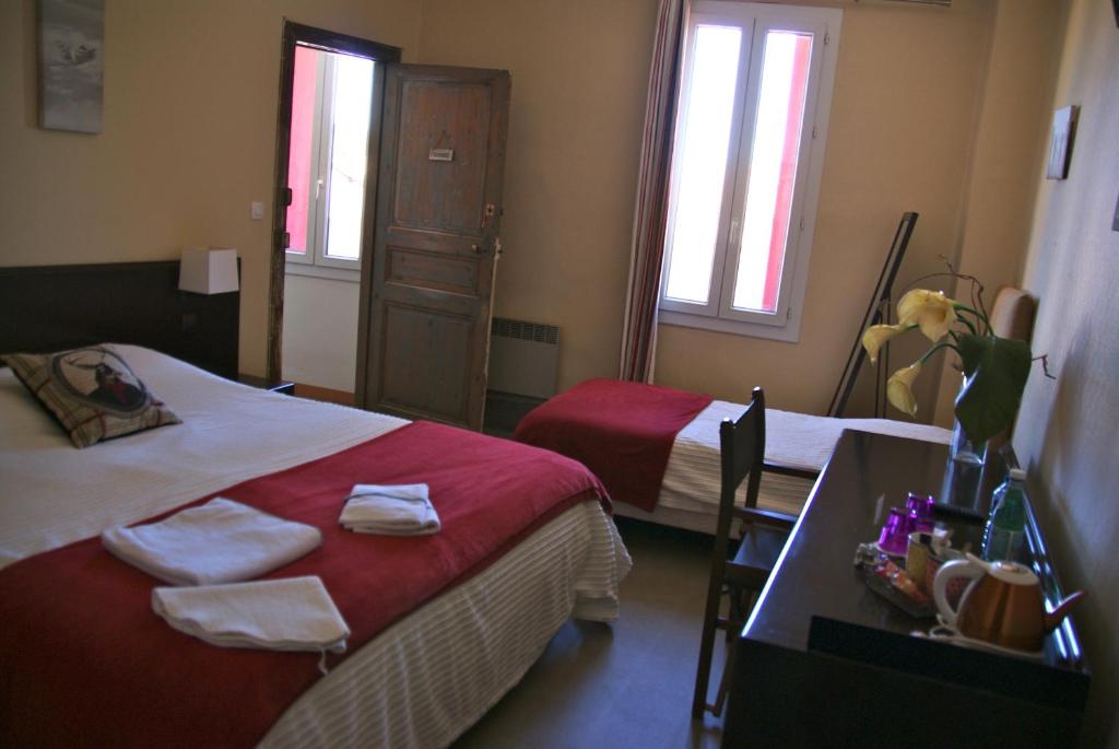 a bedroom with two beds and a table with towels at Le Bistrot Vinaigrette in Prades-le-Lez