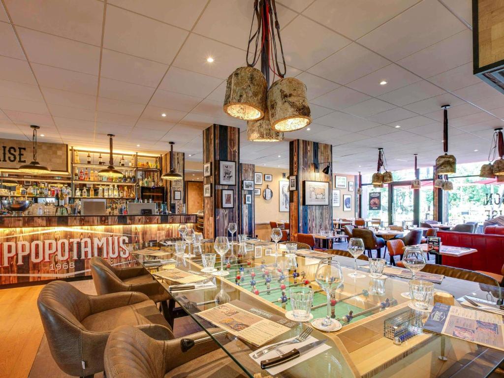 ein Restaurant mit Glastisch und Stühlen in der Unterkunft Novotel Bordeaux Mérignac in Mérignac