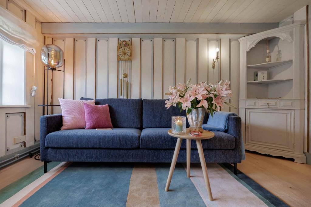 a living room with a blue couch and a table with flowers at Im Lütten in Braderup