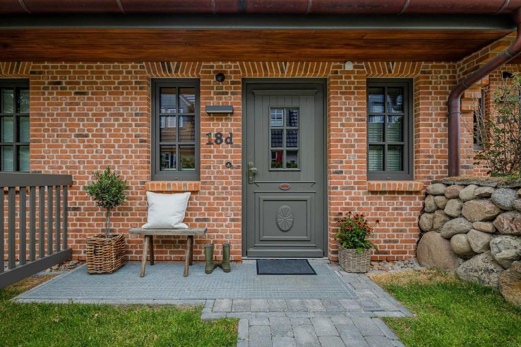 a brick house with a gray door and a chair at Haus Möhre in Tinnum