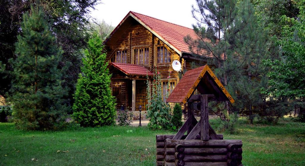 una cabaña de madera con un reloj delante en Peresvet Park Hotel, en Verkhnyaya Akhtuba