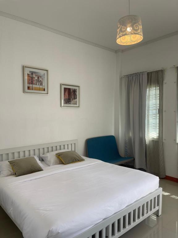 a bedroom with a large white bed and a blue chair at Baan Klang Khao Mountain Viewบ้านกลางเขา เมาเทนวิว in Ban Pang Asok