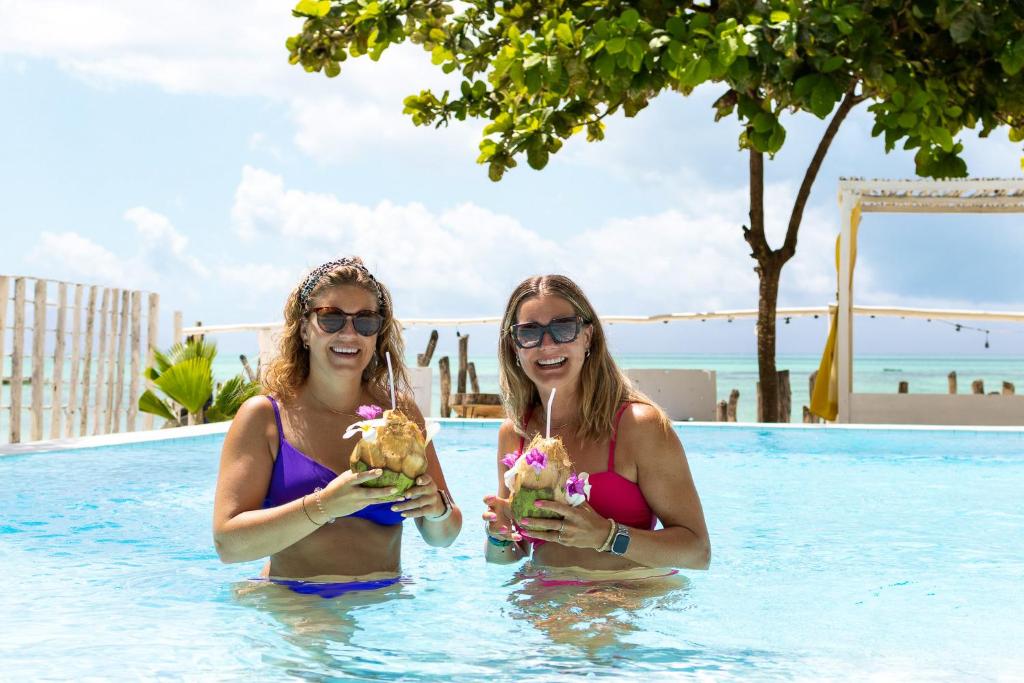 zwei Frauen im Schwimmbad mit Getränken in der Unterkunft ZAN Uhuru Jambiani Beach in Bwejuu