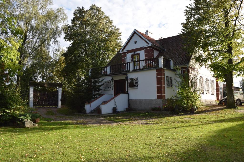 a large white house with a balcony and a yard at Villa Maximilian in Srokowo
