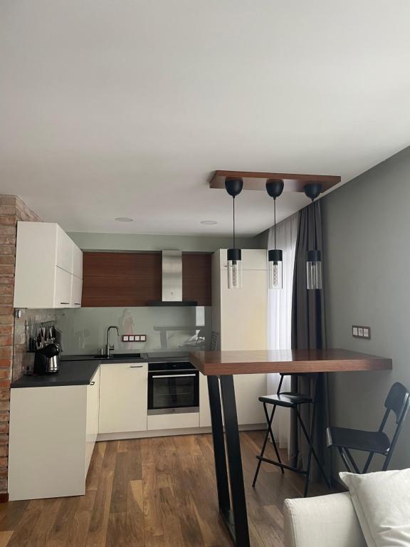 a kitchen with white cabinets and a wooden table at TK apartamenti 3 in Rēzekne