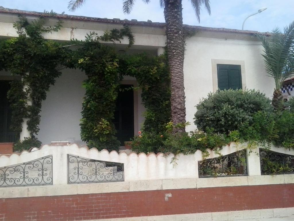 uma casa com uma cerca e uma palmeira em Casa del Glicine em Marina di Ragusa