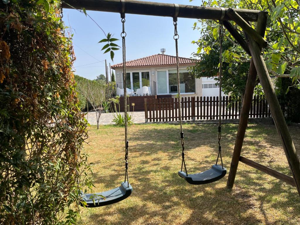 two swings in a yard with a house at Porta da Seca casa con jardín y asador Rías Baixas in Poio