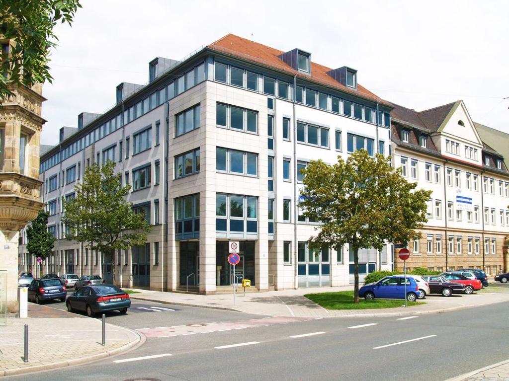 een groot wit gebouw met auto's ervoor geparkeerd bij Hotelappartements BR in Fürth