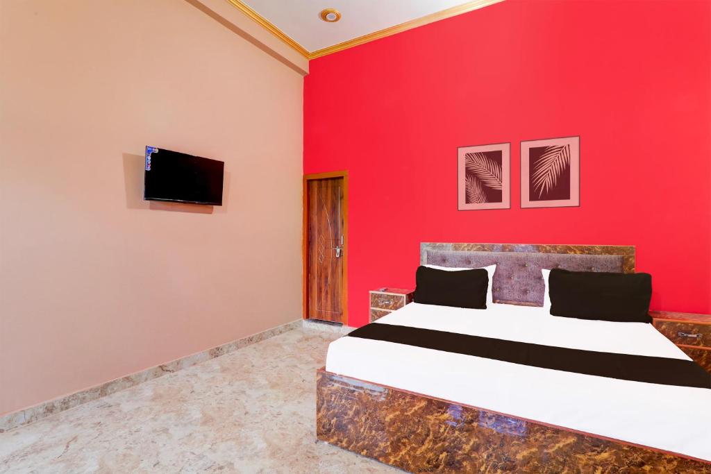 una camera da letto con una parete rossa, un letto e una TV di Hotel O Kashvi Hotel a Misrikh