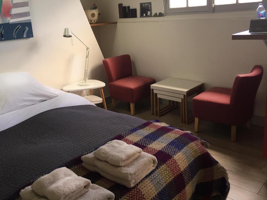 a bedroom with a bed with two chairs and two towels at Studio 29 in Honfleur