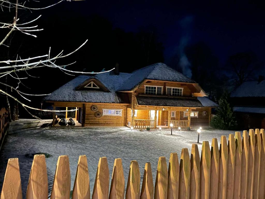 una casa di legno di notte con una recinzione di Močiutės sodyba a Latežeris