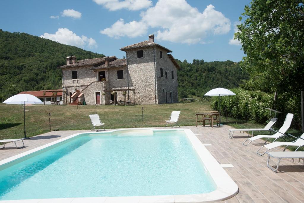 a swimming pool in front of a building with a house at Agriturismo La Commenda-Adults Only in Cascia