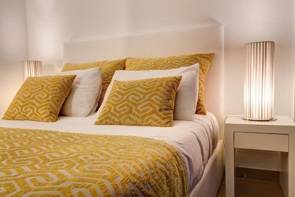 a bed with yellow and white sheets and pillows at Bracara Guest House "Campo Novo" in Braga