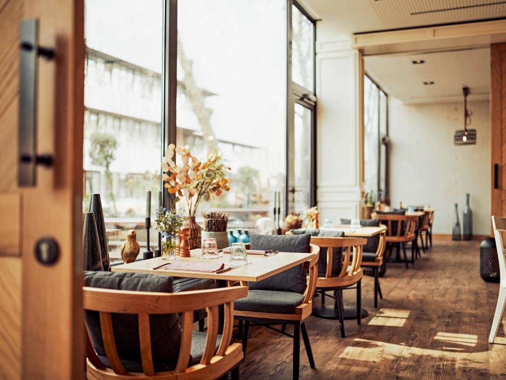 a restaurant with tables and chairs and windows at Hotel Mondial am Dom Cologne MGallery in Cologne