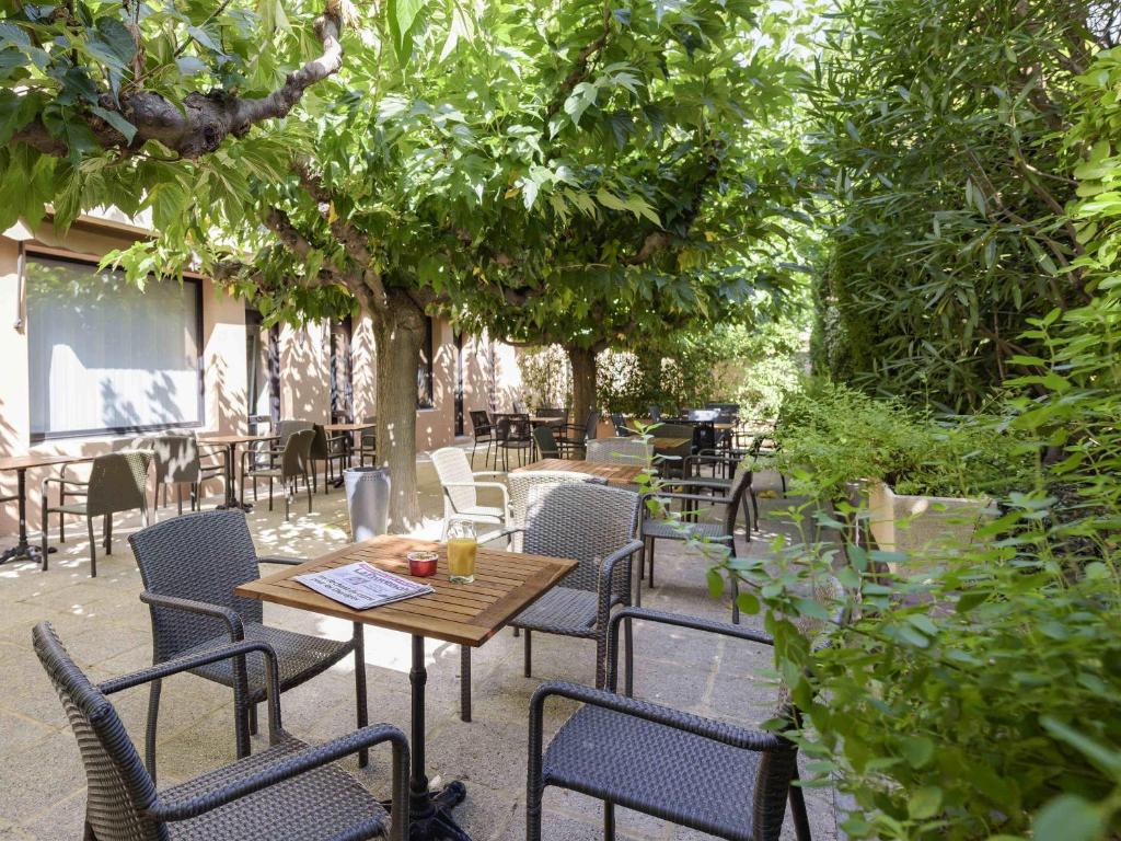 an outdoor patio with tables and chairs and trees at ibis Avignon Centre Pont De L'Europe in Avignon