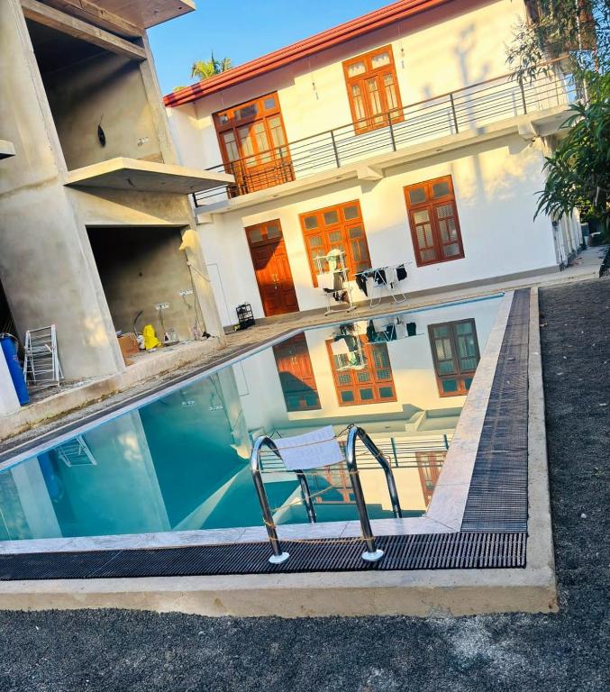 a swimming pool with a chair in front of a building at Mango Tree Weligama in Weligama