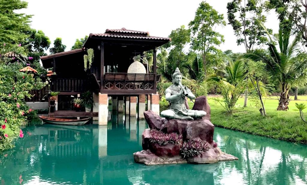a statue in the middle of a pool of water at Thakrayang Brass Artisan Home Stay in Ban Tha Krayang
