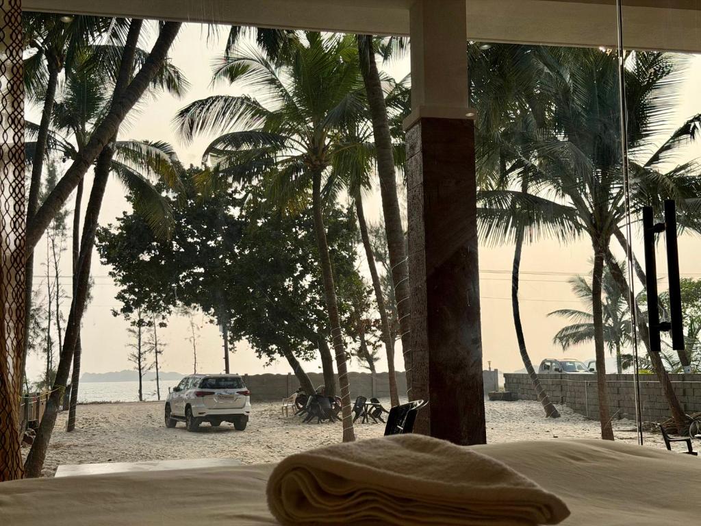 a bedroom with a view of a beach with palm trees at Navasharada's White Sand Beach House in Udupi