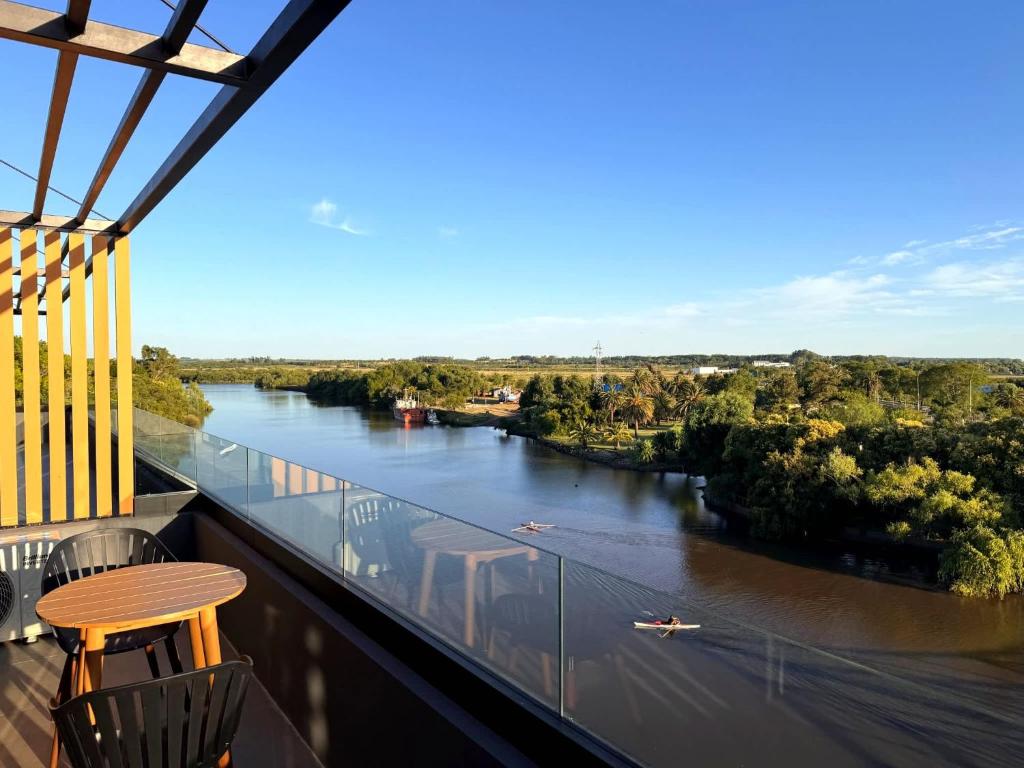 een balkon met een tafel en stoelen en uitzicht op een rivier bij Carmelo Postal by Puerto Dijama in Carmelo
