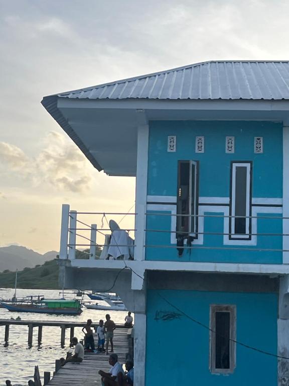 a blue building on a dock next to the water at Fanni tour komodo in Rancakole