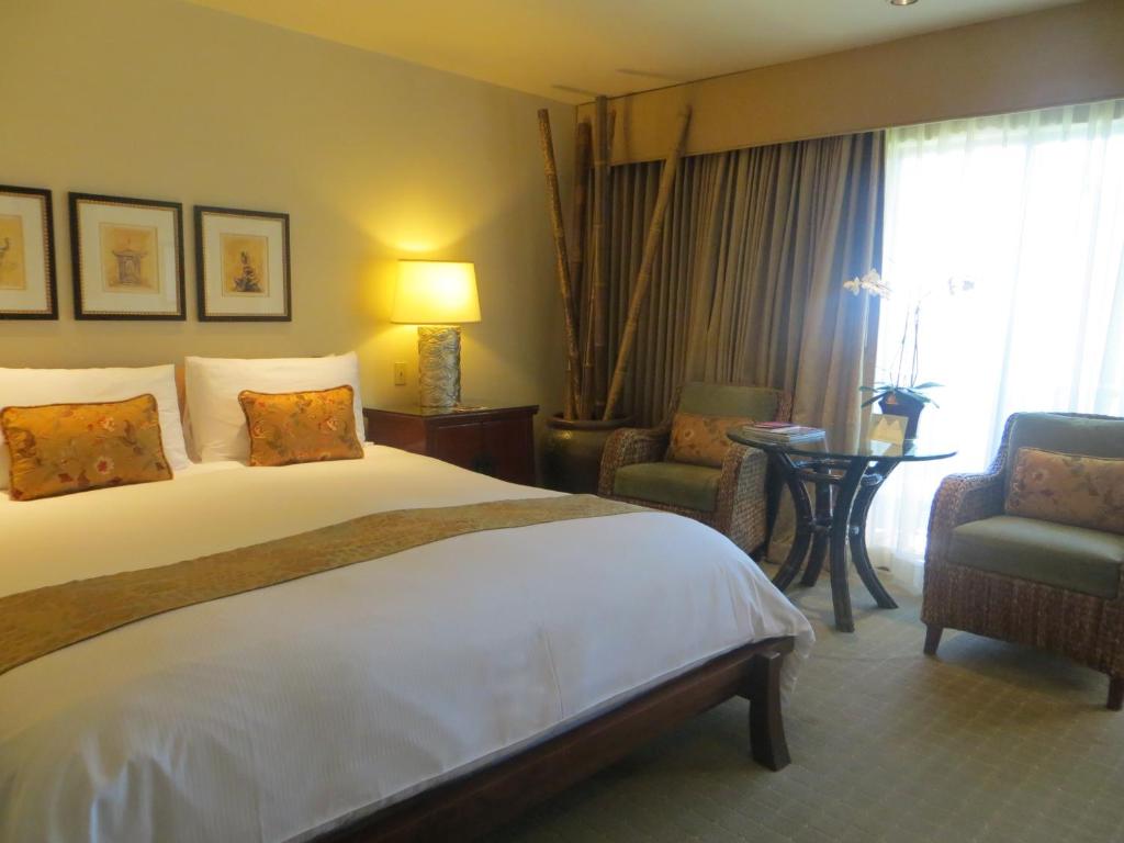 a hotel room with a large bed and two chairs at Tradewinds Carmel in Carmel