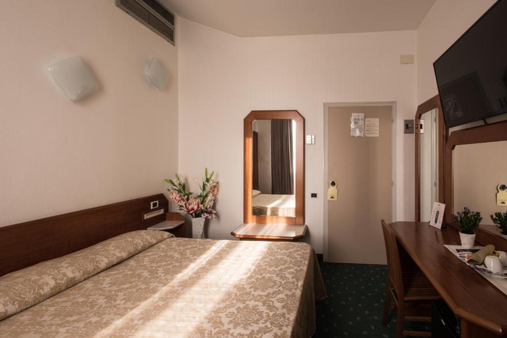 Pokój hotelowy z łóżkiem, biurkiem i lustrem w obiekcie Hotel Centrale w mieście Piombino