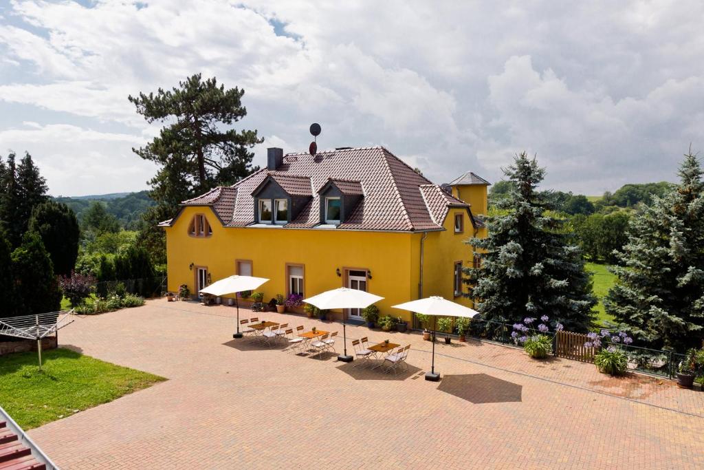 ein gelbes Haus mit Stühlen und Sonnenschirmen davor in der Unterkunft Pension Kroppental in Naumburg