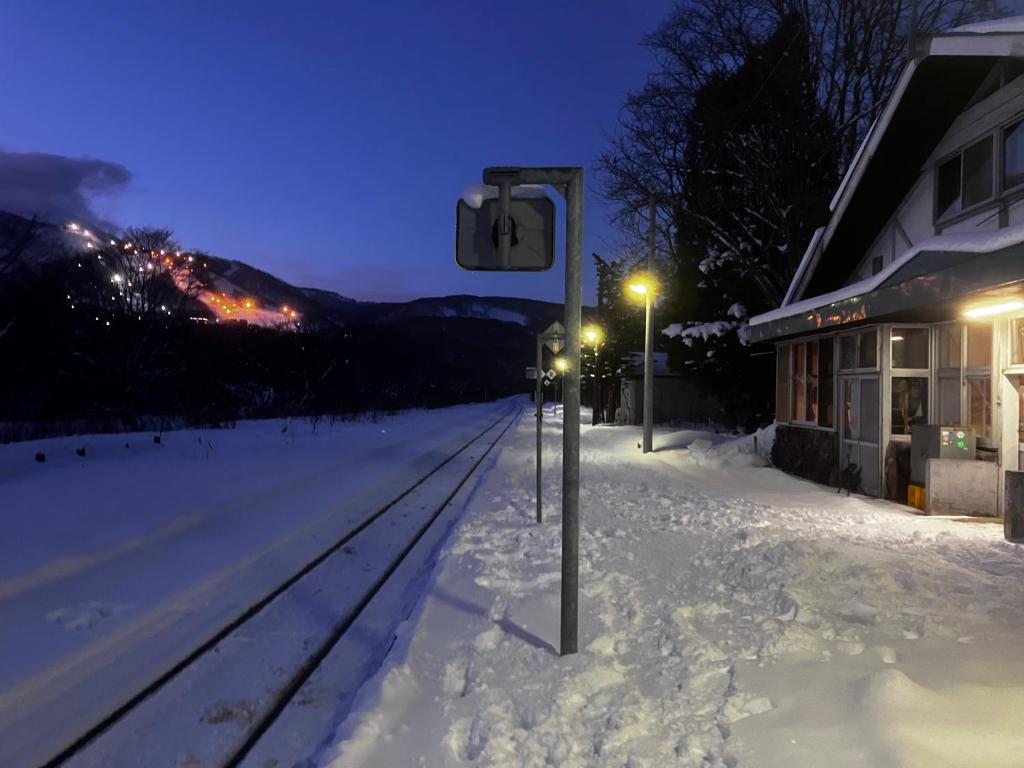 a snow covered street with a train station at night at Hirafu Station Guesthouse - Ekinoyado Hirafu in Kutchan