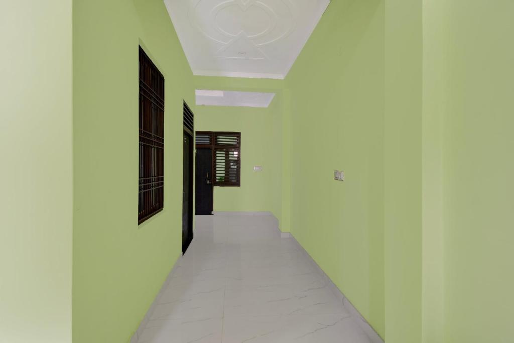 einen Flur mit weißen Wänden und einer schwarzen Tür in der Unterkunft SPOT ON Hotel The Baithak & Restaurant in Etāwah