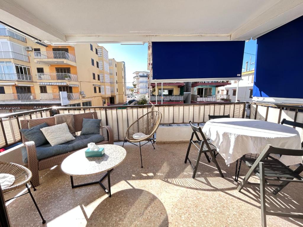 a balcony with a tv and a couch and chairs at On the Beach Oliva in Oliva