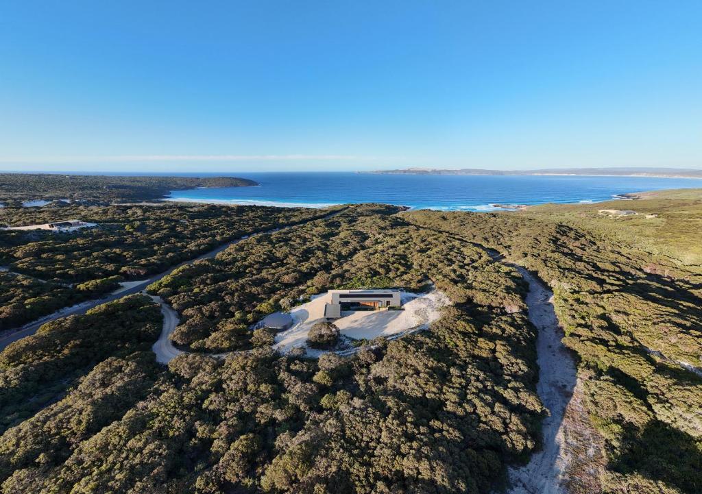 an aerial view of a house on a hill next to the water at Native Dog Cabin in Bremer Bay
