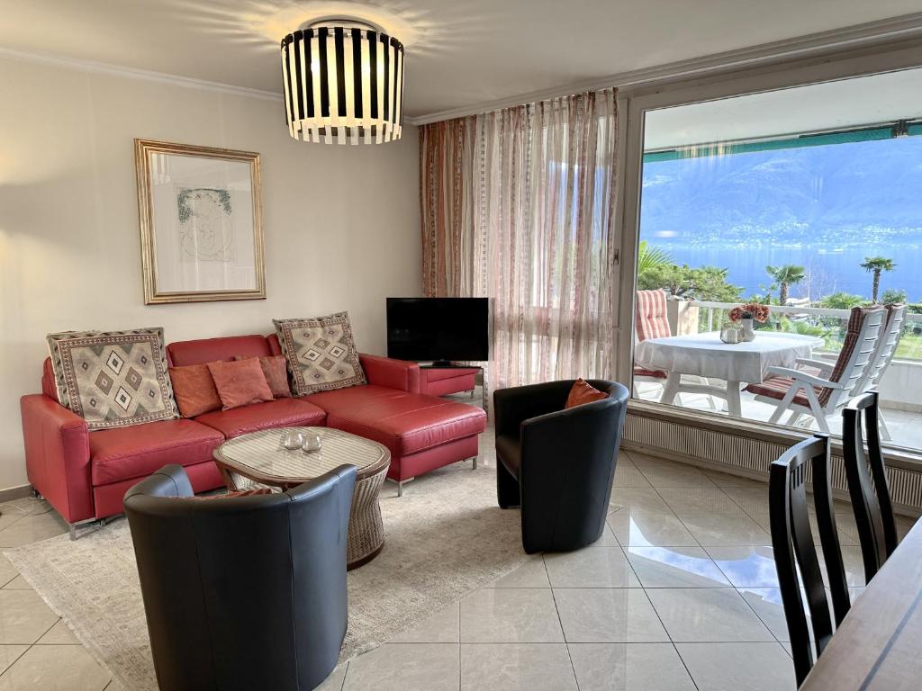 a living room with a red couch and a table at Portofino by Fewotessin in Brissago