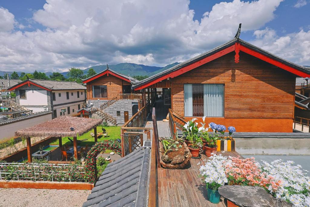 una casa con fiori su una terrazza di legno di Dawnscape snowmountain viewing Courtyard - Baisha old town a Lijiang