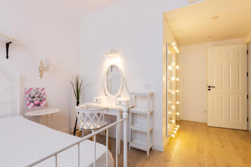 a white bedroom with a vanity and a mirror at White House in Madinaty