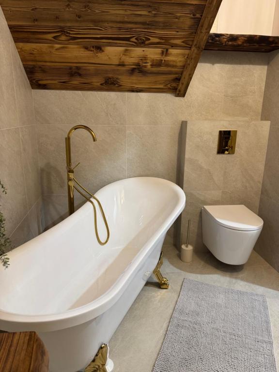 a bathroom with a white bath tub and a toilet at Villa Podhalańska 1959 in Biały Dunajec