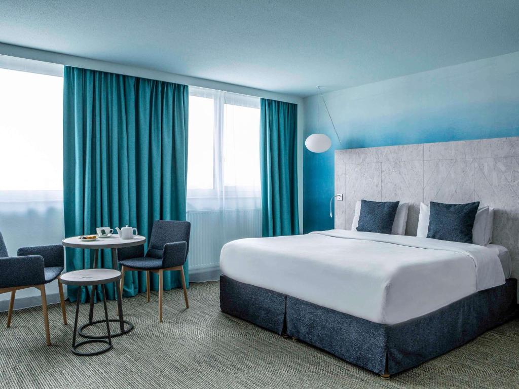 een hotelkamer met een bed, een tafel en stoelen bij Mercure Vannes Le Port in Vannes