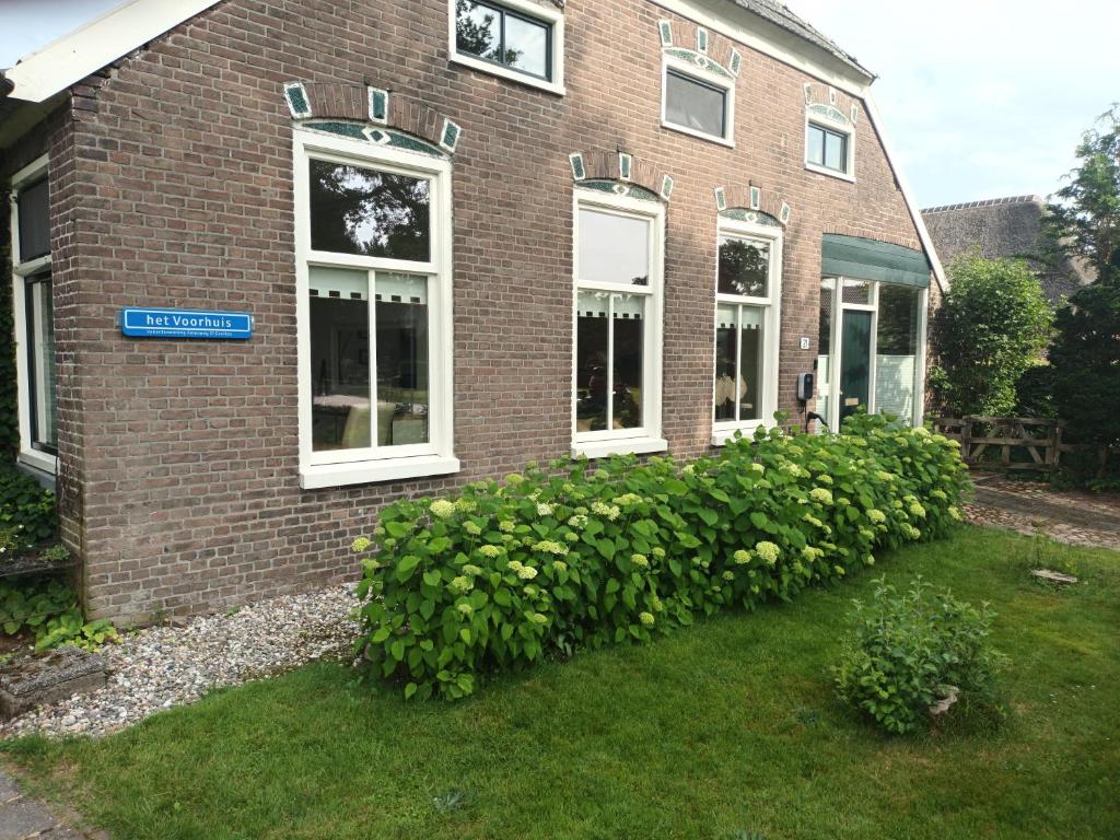 een bakstenen huis met een blauw bord erop bij Het Voorhuis in Grolloo
