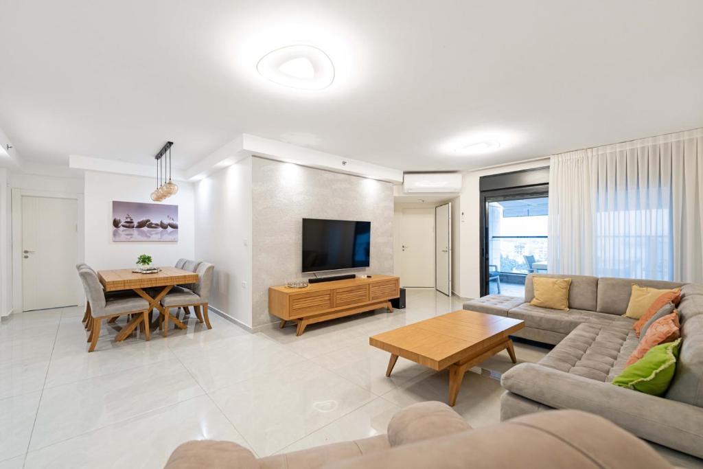 een woonkamer met een bank, een tv en een tafel bij Spacious Family Luxury Getaway in Ashdod