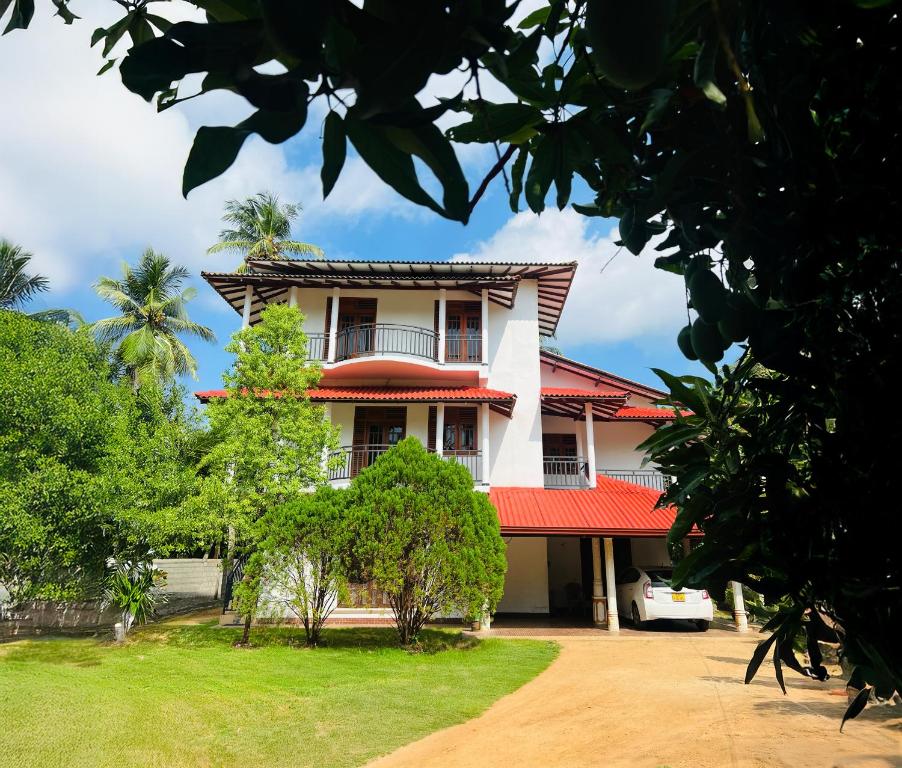 een huis met een rood dak en een tuin bij Yala Mangora Inn in Tissamaharama