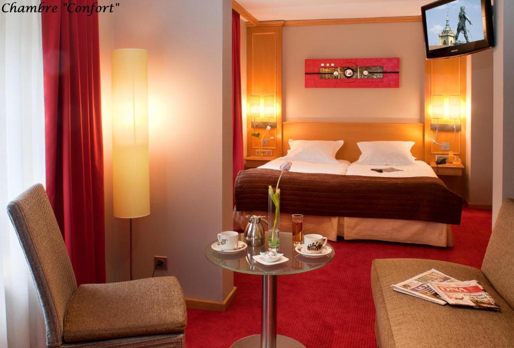a hotel room with a bed and a table at Hôtel Le Rapp in Colmar