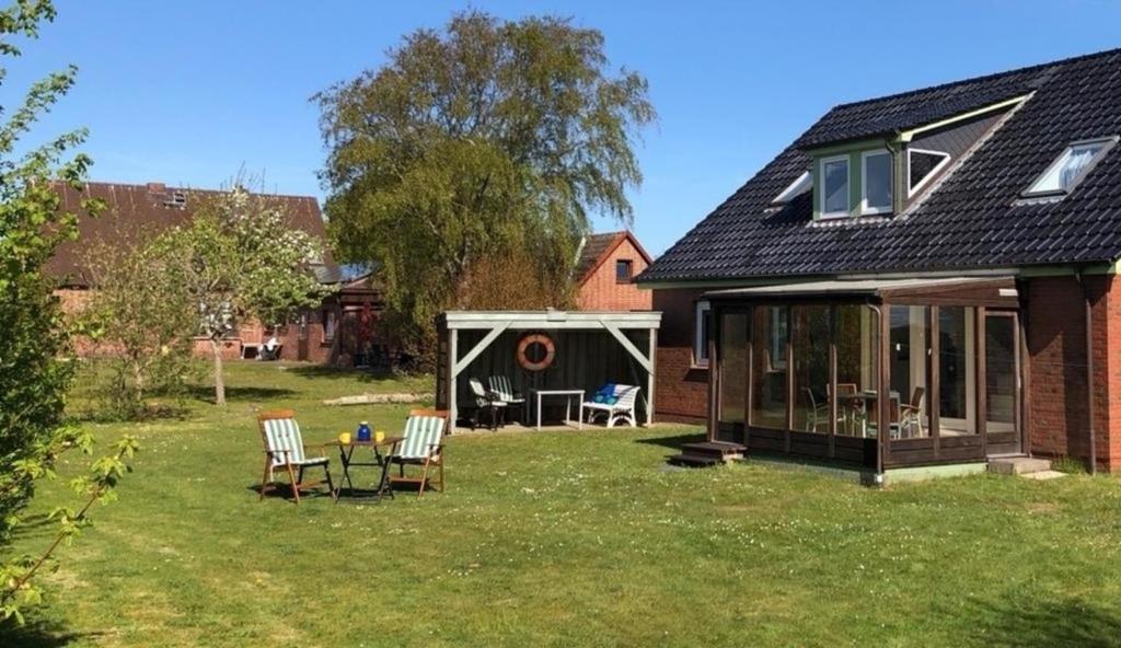 a house with two chairs and a table in the yard at Küstenhuus in Utersum